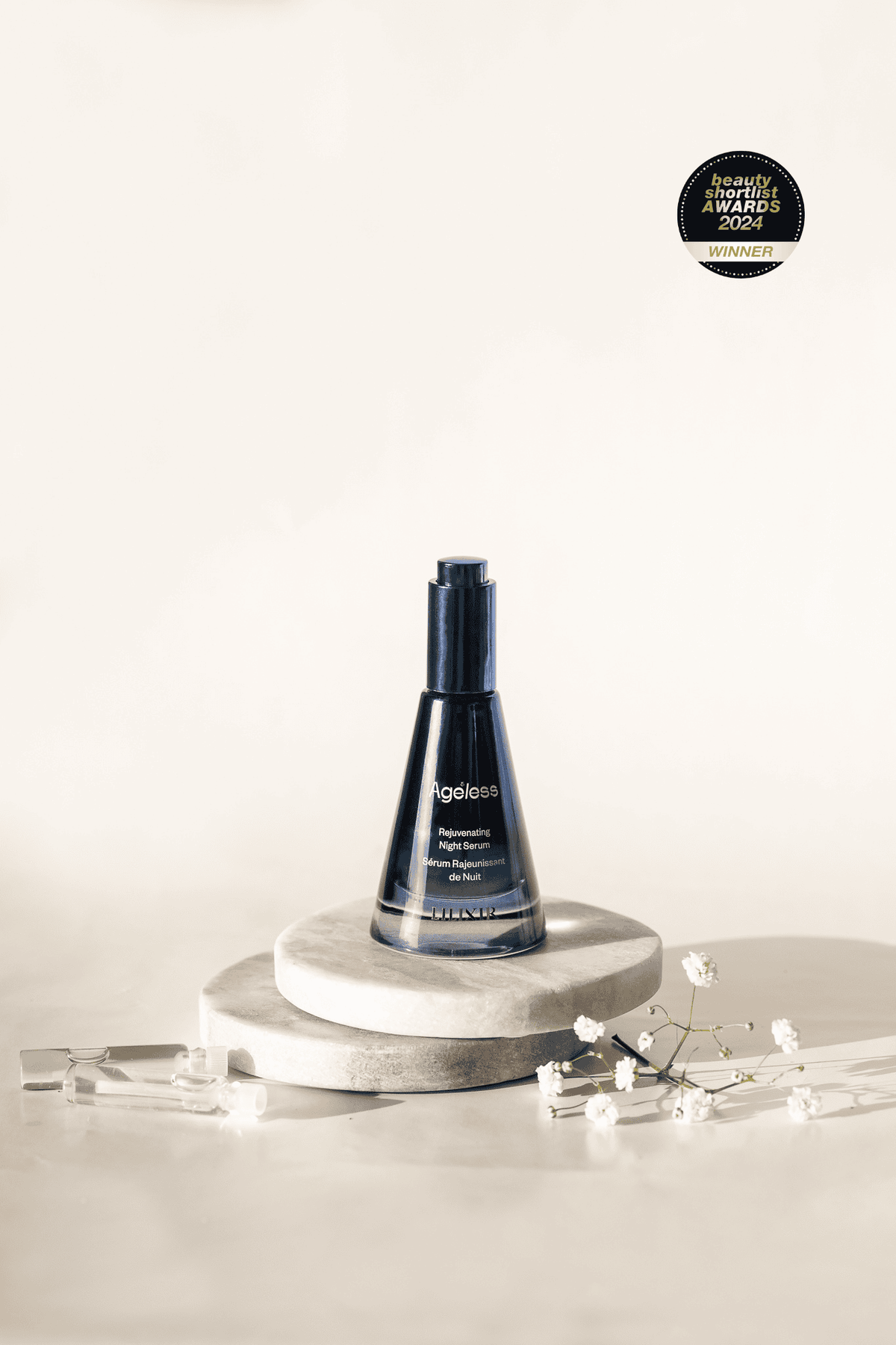 lilixir ageless rejuvenating night serum, a blue bottle on a white background with a decorative award above it