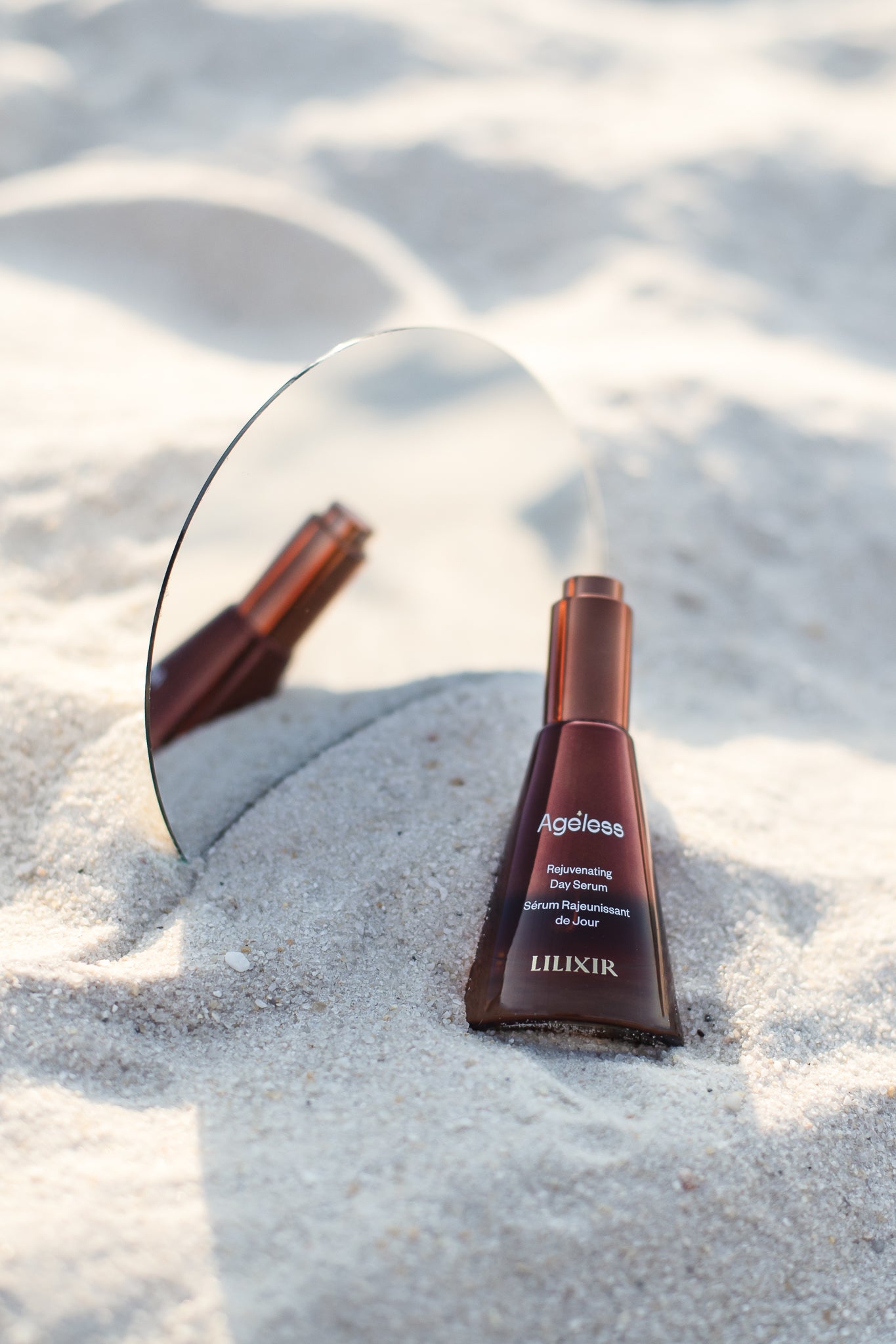 Lilixir skincare bottle on sand with mirror reflection