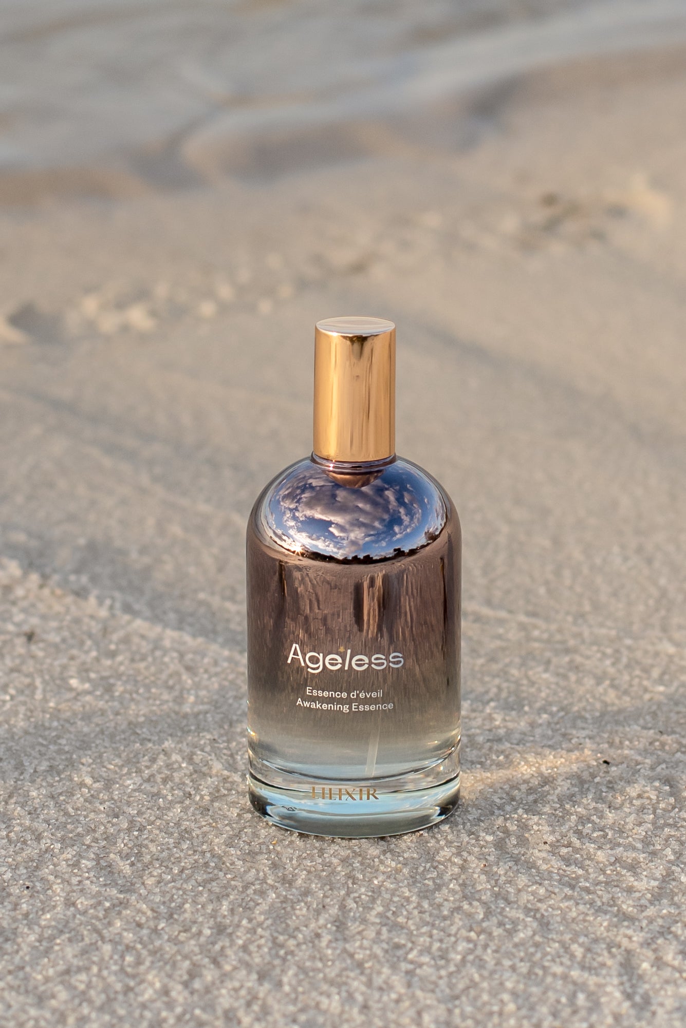 lilixir awakening essence bottle labeled 'Ageless' on sandy ground