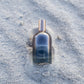 Bottle of 'LILIXIR Ageless Awakening Essence'  on sandy ground