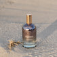 Bottle of 'LILIXIR Ageless Awakening Essence'  on a sandy surface