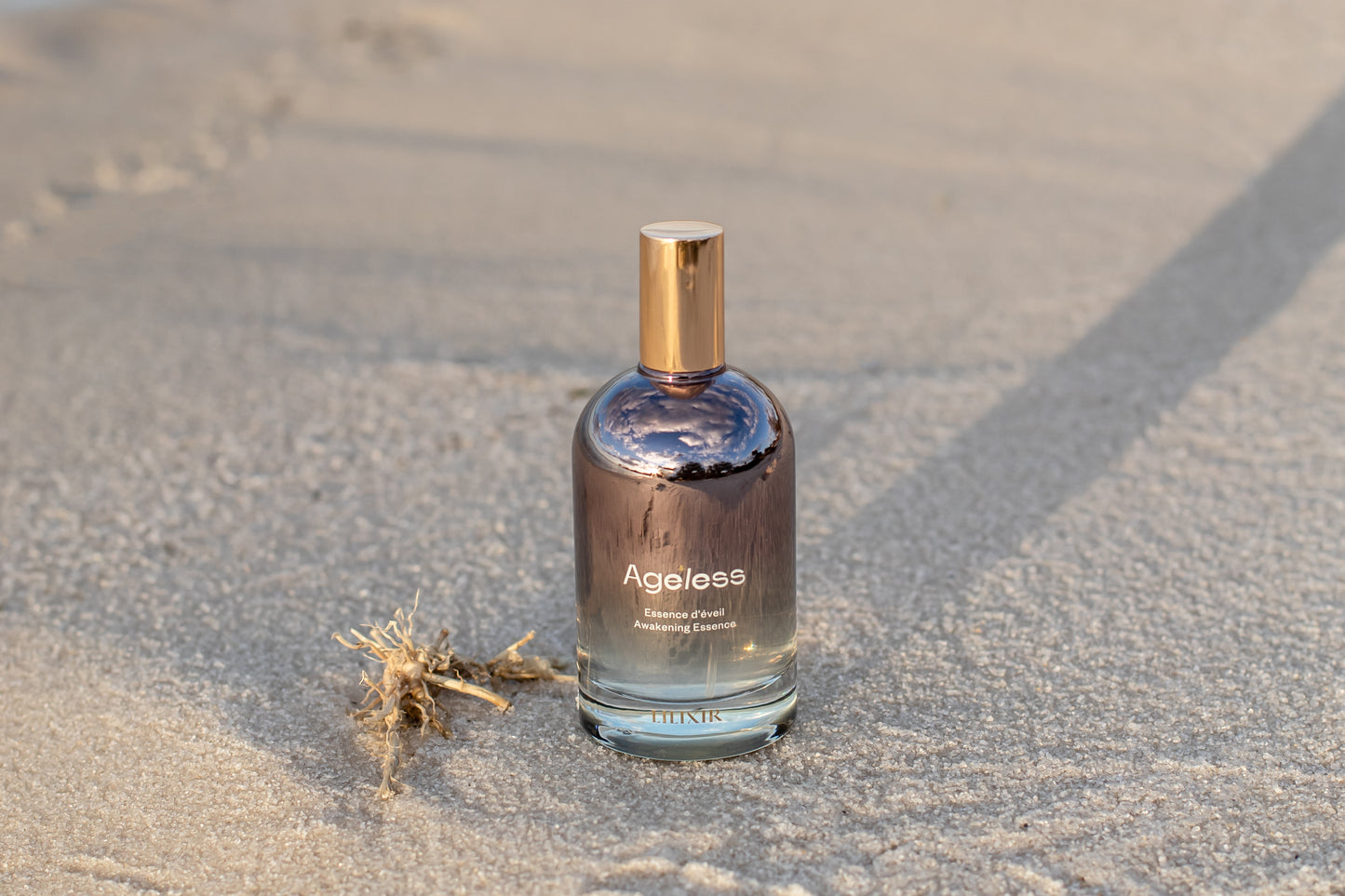 Bottle of 'LILIXIR Ageless Awakening Essence'  on a sandy surface