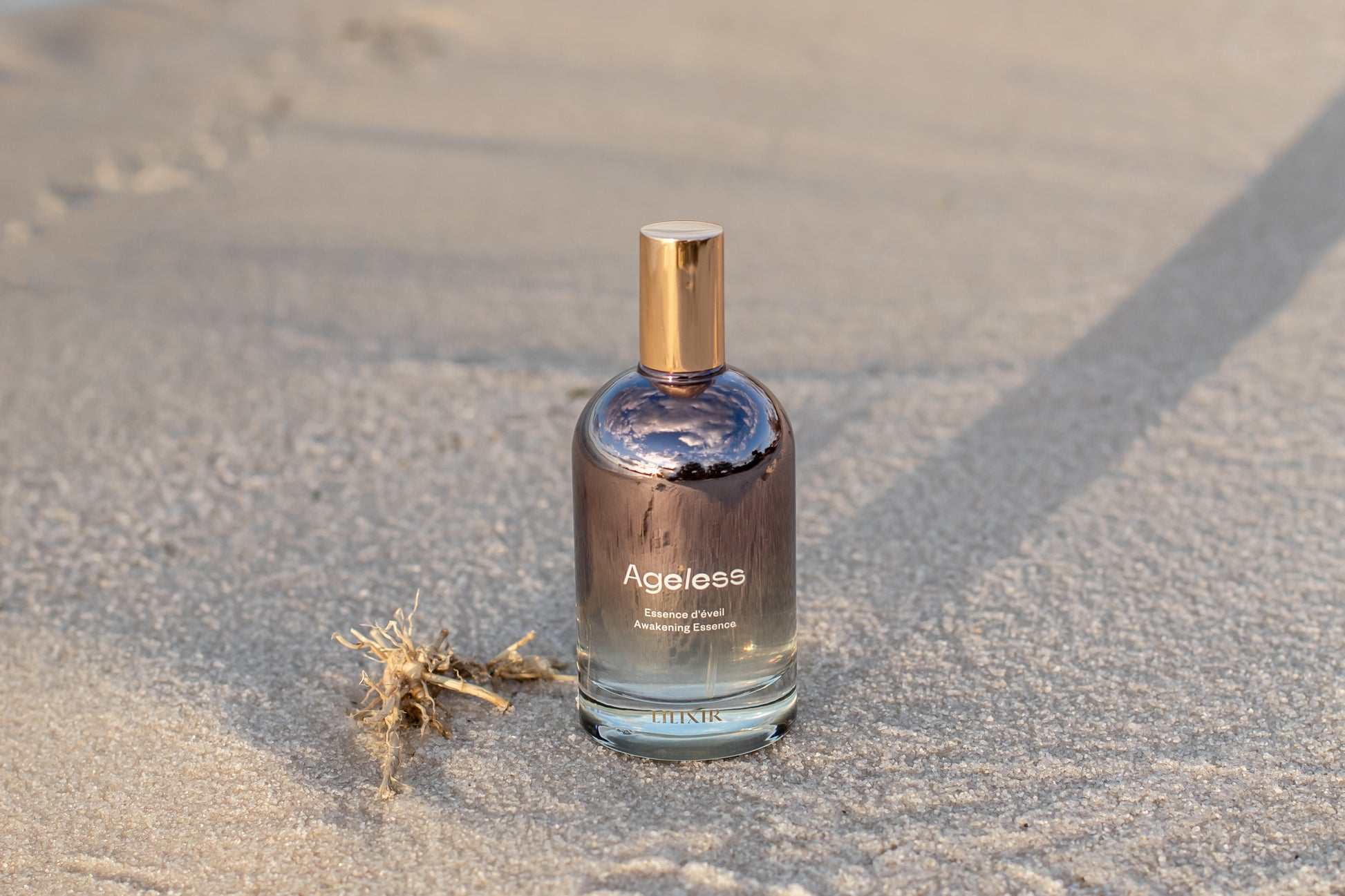 Bottle of 'LILIXIR Ageless Awakening Essence'  on a sandy surface