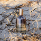 LILIXIR Ageless Awakening Essence' bottle on a sandy beach with dry grass