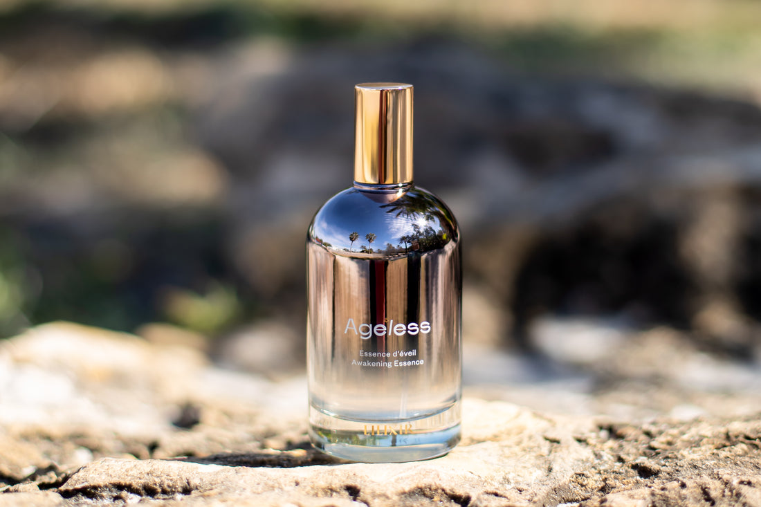 Bottle of Ageless Awakening Essence on a rock with a blurred natural background