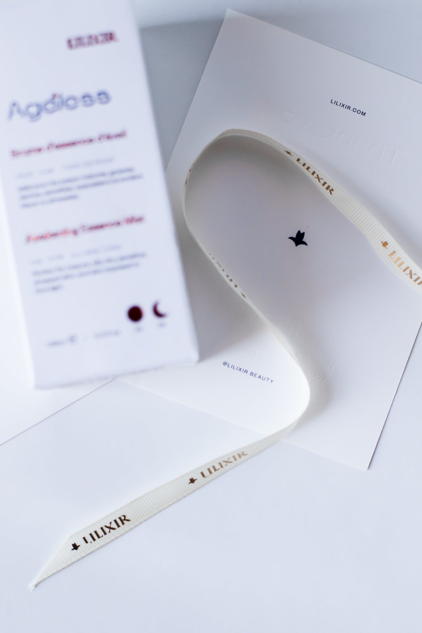 LILIXIR packaging, ribbon and card on a white surface with a product packaging in the background.