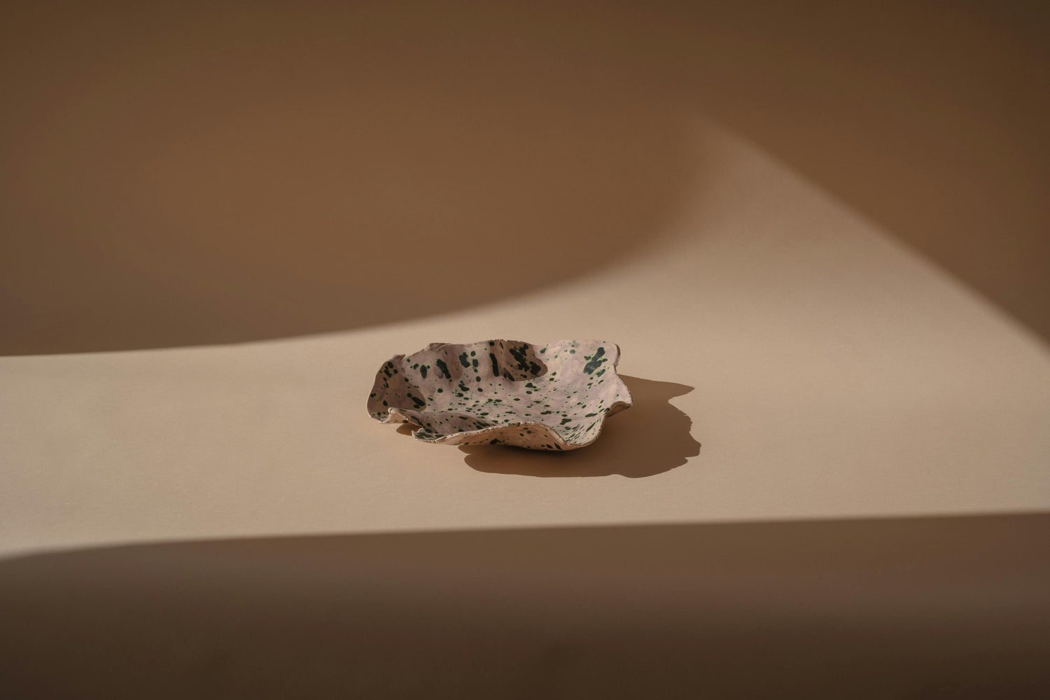 Small speckled stone on a beige surface with soft shadows