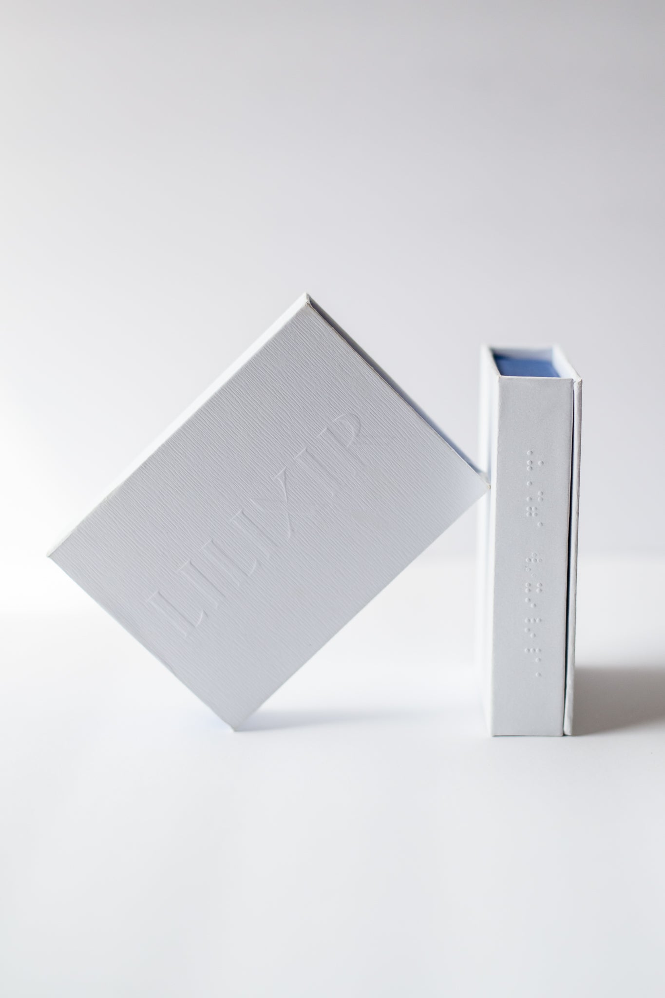 Two white boxes of lilixir gua sha on a light gray background