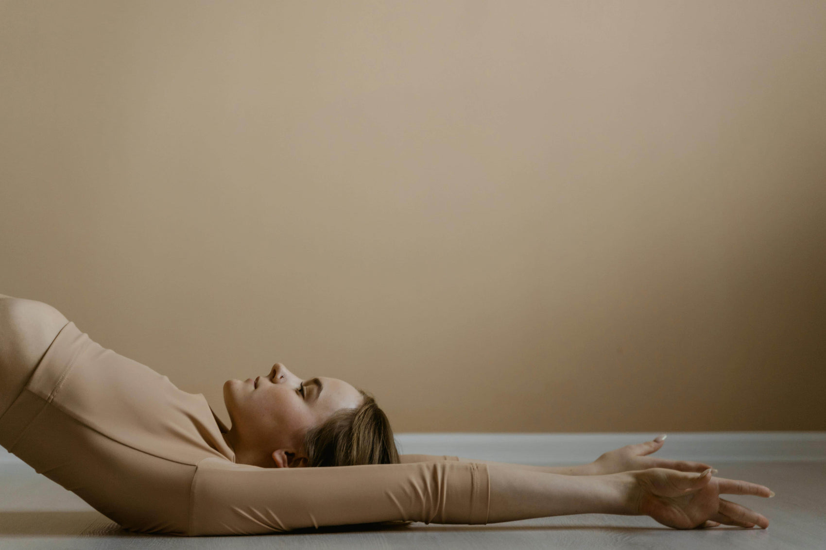 Person lying on a beige surface with a plain background