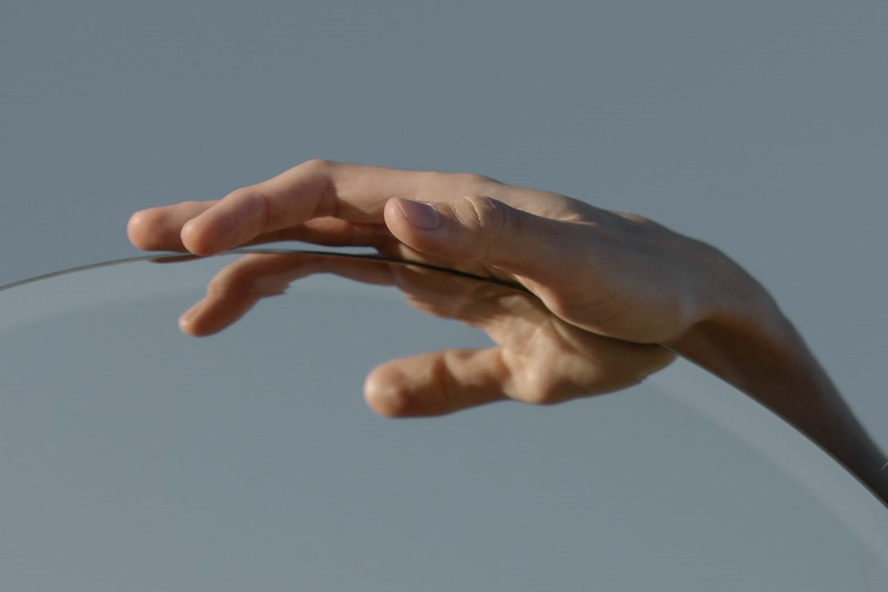 Hand touching a clear glass surface against a neutral background